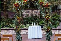 a bright rustic fall wedding aisle with pumpkins, colorful blooms and greeneyr and a matching arch done with the same blooms