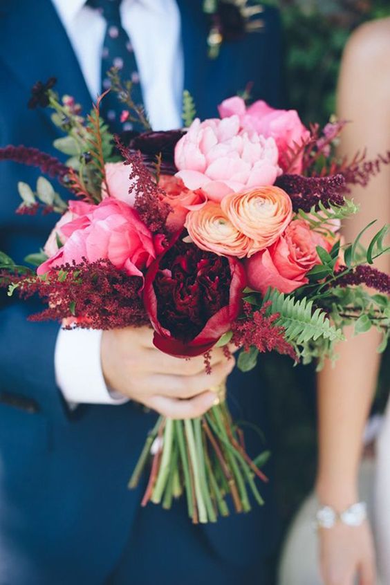 a bright wedding bouquet of pink, deep red and orange blooms, greenery and deep purple flowers for a bright fall wedding