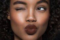 a chic makeup with perfectly matted skin, a touch of blush and highlighter, fluffy eyebrows and a dark lip