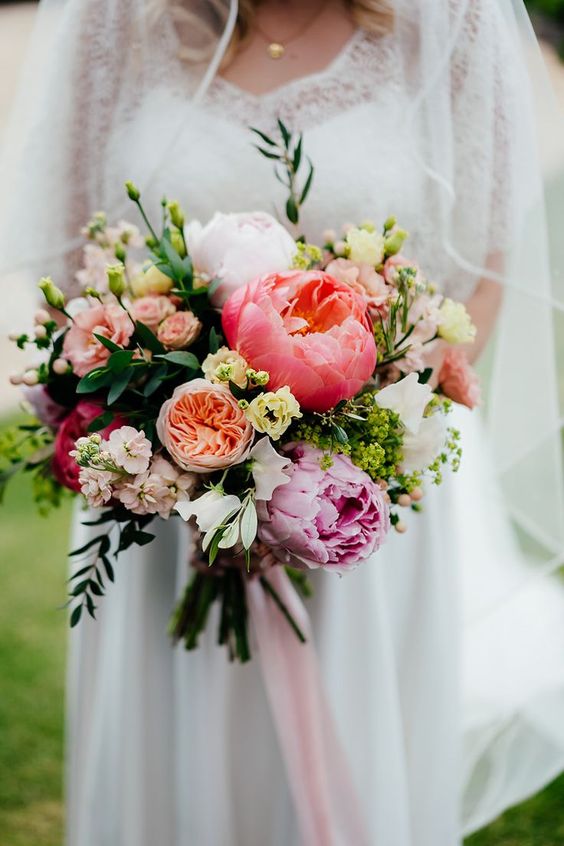 a chic pastel wedding bouquet of greenery, coral, pink and blush peonies, white blooms and greenery is amazing for spring