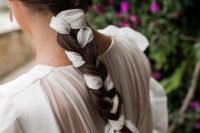 a classic braid spruced up with a white ribbon that matches the wedding dress and gives interest to the simple hairstyle