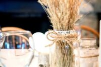 a classy rustic wedding centerpiece of a mirror, a mason jar with wheat and a tree branch is an easy to realize decoration