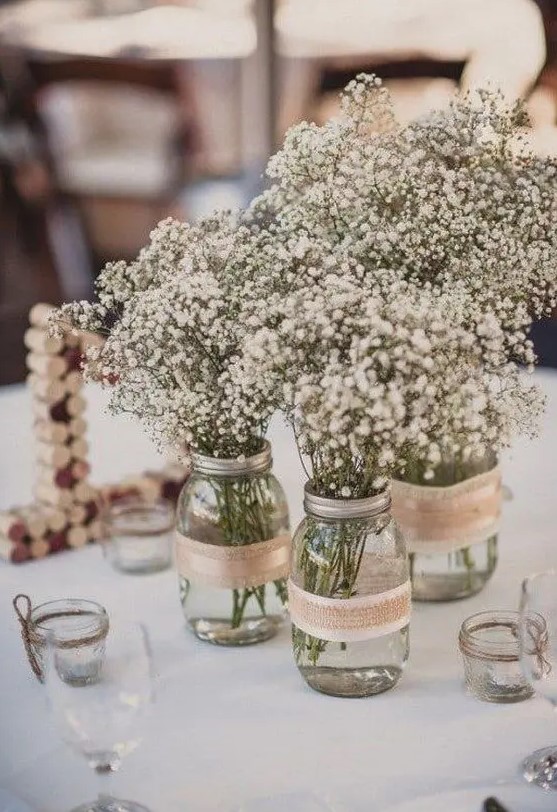a cluster rustic wedding centerpiece of mason jars with burlap and white baby's breath is a cool idea for a rustic wedding