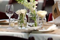 a cluster wedding centerpiece of mason jars, white blooms and candles around is a cool idea for a rustic wedding