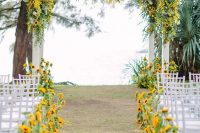 a colorful fall wedding aisle lined up with bold sunflowers and with a matchign wedding arch covered with them, too
