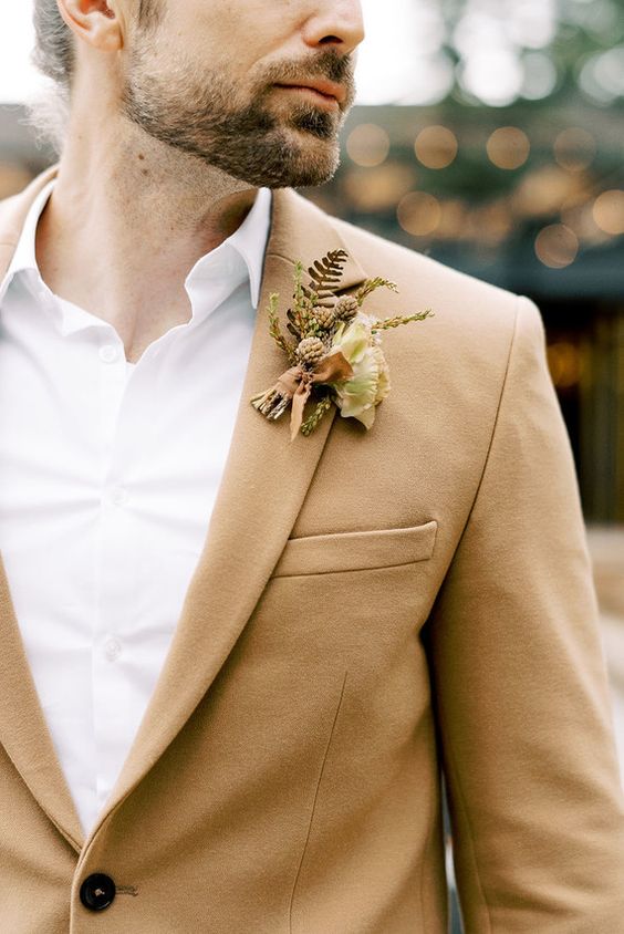 a cool and simple fall wedding boutonniere with neutral blooms, foliage and textural greenery plus brown ribbons for a neutral fall wedding