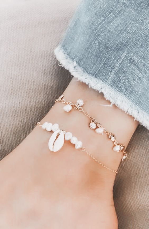 a duo of gold chain anklets with baroque pearls, seashell charms and pearls and a large shell are amazing go a boho beach bride