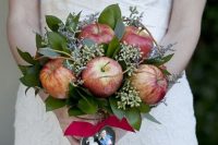 a fall wedding bouquet of apples, foliage and seeded eucalyptus plus a burgundy ribbon and a heart with photos