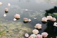 a garden pond styled for the wedding with floating pink roses and candles is a very lovely idea to go for