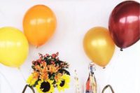 a glam and bright fall bridal shower bar with a colorful tassel garland with letters and a bright polka dot cart with blooms and balloons