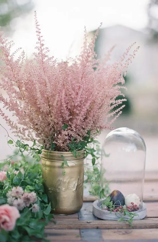 a gold mason jar with greenery and pink astilbe, a greenery and pink flower runner and a cloche with some fruit