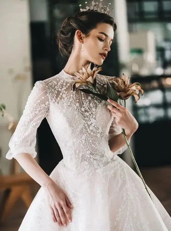 a jaw-dropping lace applique and embellished wedding ballgown with a high neckline and short sleeves plus a crown