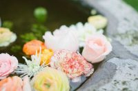 a large bowl with pastel and bold blooms floating inside is a lovely idea for a refined and chic wedding