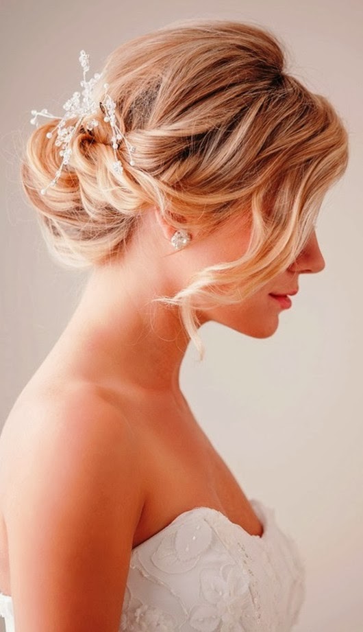 a low twisted chignon with a rhinestone hairpiece and a long bang on one side