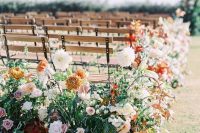 a lush fall wedding aisle with blush and dusty pink blooms, rust and orange ones and lots of greenery and bold foliage
