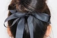 a messy twisted top knot with a graphite grey ribbon bow is a very refined and chic idea for a pretty bridal look