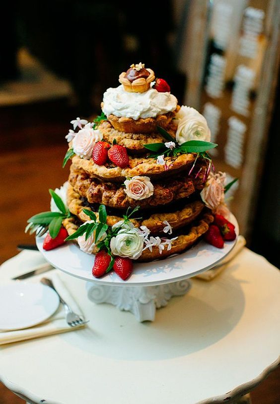 a naked cookie wedding cake topped with a tart and a cupcake, strawberries and white blooms and greenery is a lovely idea