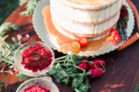 a naked wedding cake with caramel drip, fresh fruits and veggies on top and around,too