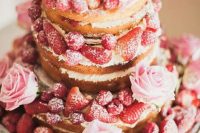 a naked wedding cake with pink roses, strawberries is a delicious-looking and lovely dessert for a summer wedding