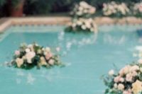 a pool with floating neutral and blush blooms and greenery is a very chic and beautiful idea for a refined wedding