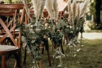 a pretty fall boho wedding aisle decorated with pampas grass and eucalyptus in bottles is a lovely idea