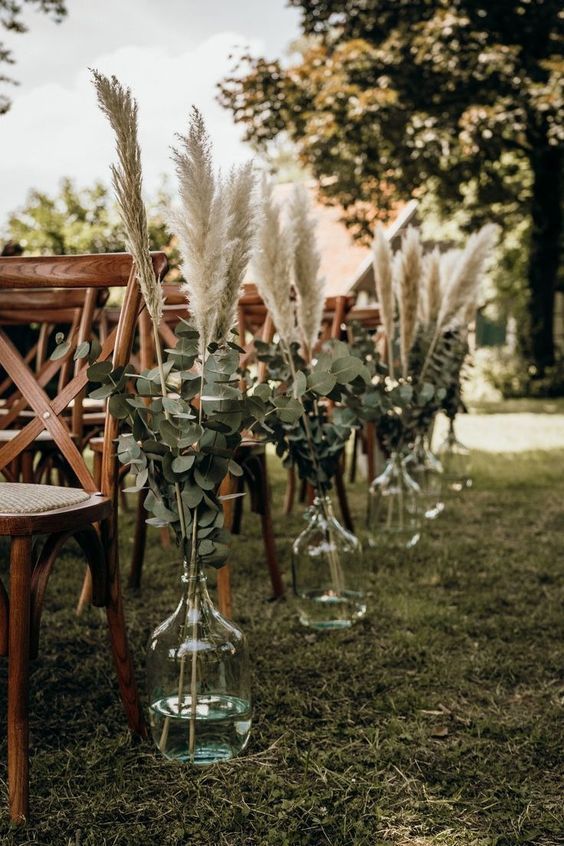 a pretty fall boho wedding aisle decorated with pampas grass and eucalyptus in bottles is a lovely idea