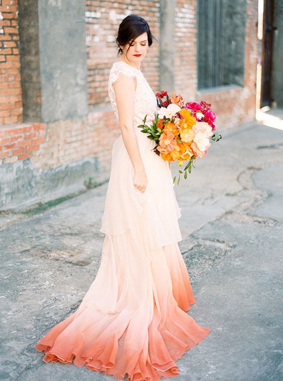 a refined wedding dress with a lace bodice, a tiered dip dye peachy pink and red skirt with a train
