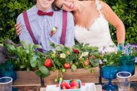 a relaxed summer wedding tablescape with a wooden box with greenery, wildflowers and strawberries is a gorgeous idea