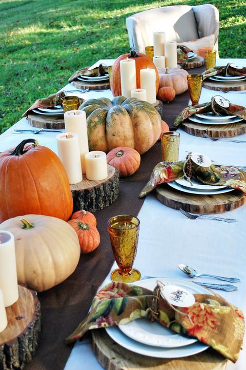 a rustic fall bridal shower setting with large natural pumpkins, pillar candles on wood slices and colorful napkins
