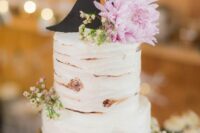 a rustic wedding cake imitating birch bark, with white blooms and greenery and a black silhouette cake topper is amazing