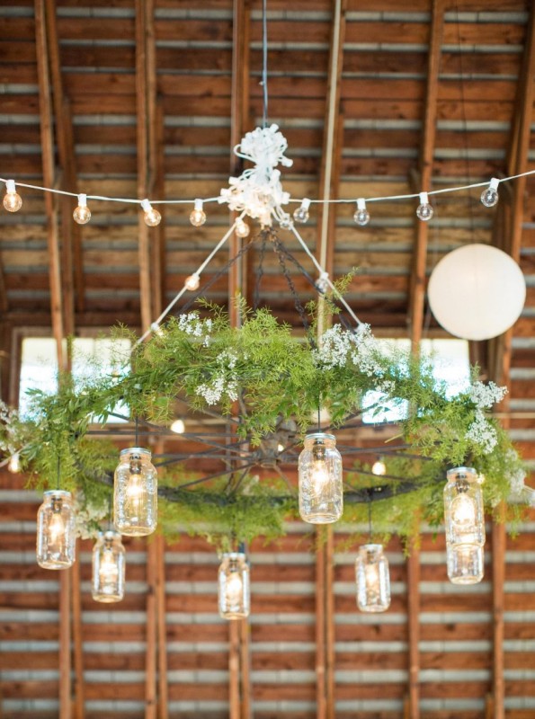 a rustic wedding chandelier of a large wheel with greenery and mason jars as lanterns is a creative DIY project