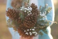 a rustic winter wedding bouquet with pinecones, baby’s breath and evergreens is a stylish and chic idea for a Christmas or just winter wedding