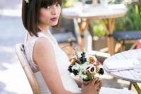 a short bob with bangs and a fresh bloom and berry hairpiece for a modern bride with a bit of edge