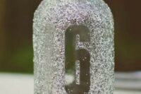 a silver glitter mason jar with a table number doubles as a candle lantern, perfect for a winter wedding with a ouch of sparkle