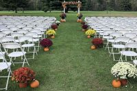 a simple rustic fall wedding aisle with pumpkins and bold potted blooms is a cool and bright idea for a fall wedding