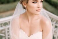 a statement floral rhinestone bridal crown with a long veil plus rhinestone earrings for a glam feel