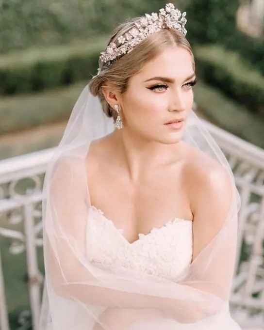a statement floral rhinestone bridal crown with a long veil plus rhinestone earrings for a glam feel