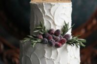 a textural white wedding cake with sugared berries and herbs, with a plywood silhouette cake topper is a lovely and cozy idea