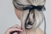 a twisted long and low ponytail turned into a low updo with an ethereal and sheer black ribbon for an accent without much drama