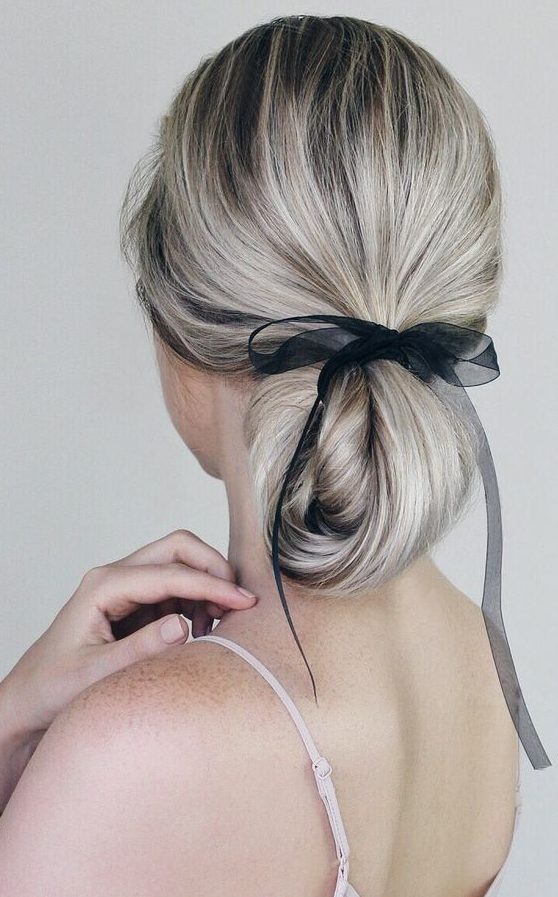 a twisted long and low ponytail turned into a low updo with an ethereal and sheer black ribbon for an accent without much drama