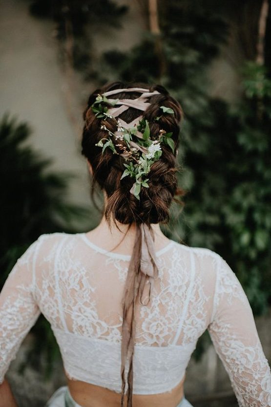 a unique braided low updo with a blush ribbon and fresh greenery interwoven looks very eye-catchy and boho