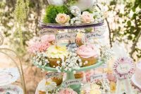 a vintage bridal shower dessert table with a cupcake stand with baby’s breath and a teapot on top, with some vintage sweets stands