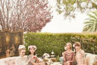 a vintage bridal shower lounge with blush sofas and a neutral tufted ottoman, flowers and vintage cake stands and bridesmaids in vintage looks