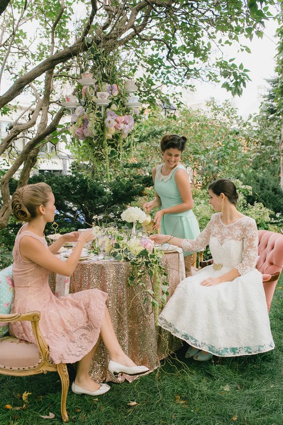 a vintage bridal shower space with an overhead floral installation with tecups, neutral blooms and greenery and ridesmaids in vintage dresses