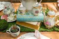 a vintage bridal shower tablescape with a greenery runner, potted succulents, pastel blooms, floral porcelain and gold cutlery