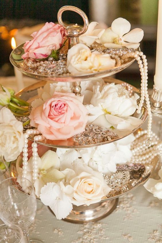a vintage cake stand with white and blush roses, pearls, vintage brooches is a lovely decor idea for a vitnage bridal shower