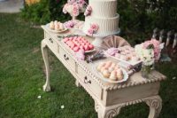 a vintage console table with a cake and lot sof sweets, macarons and pastel and neutral blooms is great for a vintage bridal shower