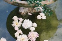 a vintage fountain with floating pastel blooms and candles on the edge is a beautiful and chic idea to go for