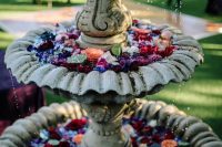 a vintage tiered fountain with lots of floating bold blooms and leaves is a very chic and bold idea for your wedding