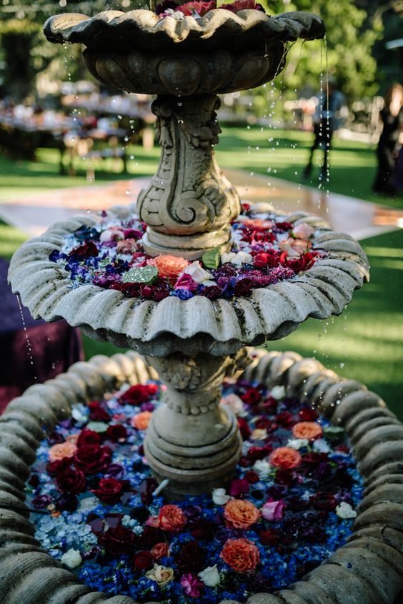 a vintage tiered fountain with lots of floating bold blooms and leaves is a very chic and bold idea for your wedding